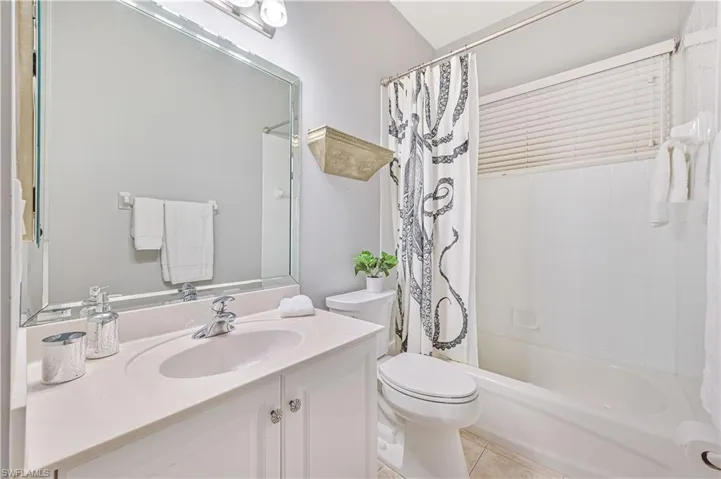 Full bathroom with shower / bathtub combination with curtain, tile patterned flooring, toilet, and vanity