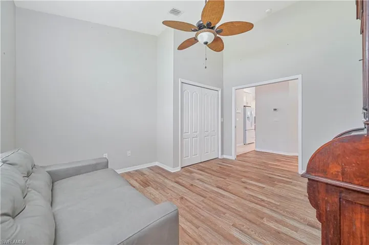 Living room featuring light hardwood / wood-style flooring, ceiling fan, and a high ceiling