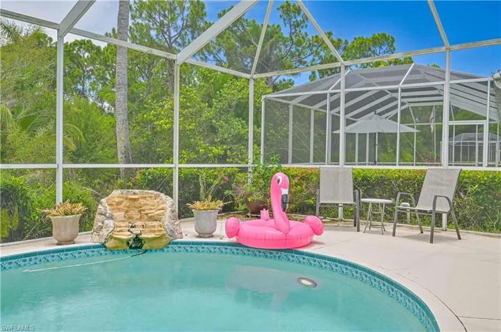 View of pool with a patio area and glass enclosure