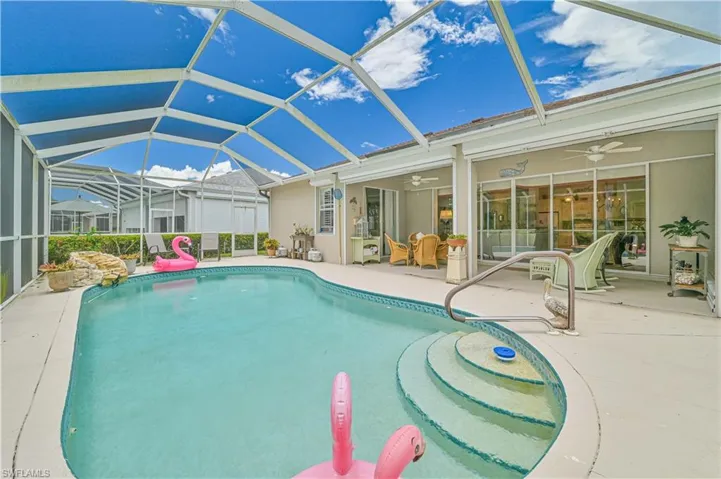 View of pool with a patio, glass enclosure, and ceiling fan