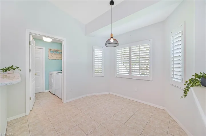 Unfurnished dining area with vaulted ceiling, independent washer and dryer, and light tile patterned floors
