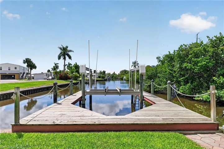 Waterfront dock featuring a boat lift, rope railings, and adjacent canal access
