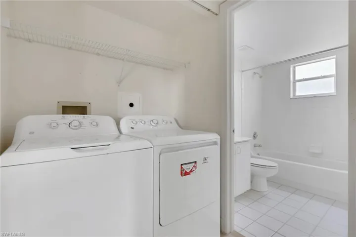 Laundry area featuring light tile patterned flooring and independent washer and dryer