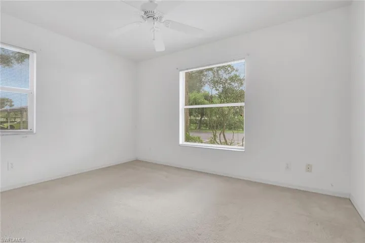 Empty room with light colored carpet and a ceiling fan