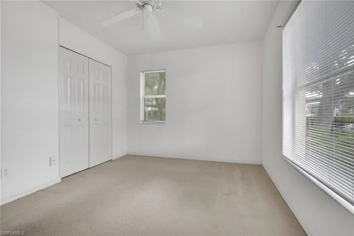 Unfurnished bedroom featuring light colored carpet, a closet, and a ceiling fan