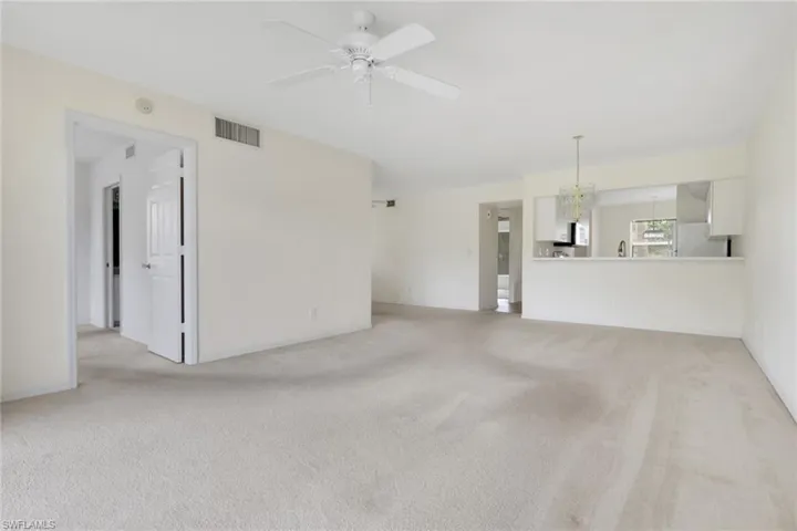 Unfurnished living room featuring light carpet, a chandelier, and a ceiling fan