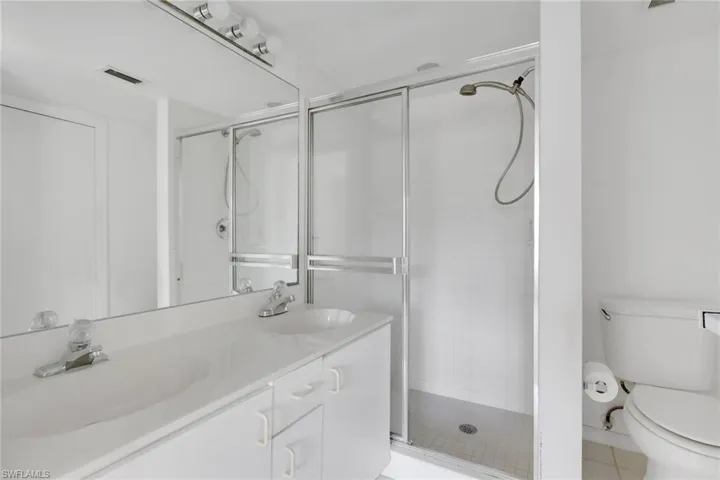 Bathroom with a stall shower, double vanity, and light tile patterned flooring