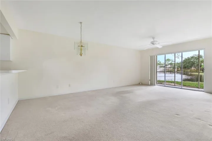 Unfurnished room featuring a water view, light carpet, a chandelier, and a ceiling fan