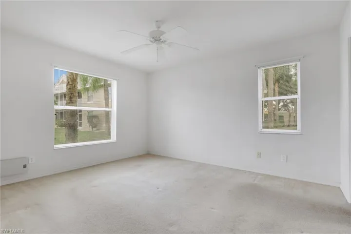 Carpeted spare room featuring a ceiling fan and baseboards