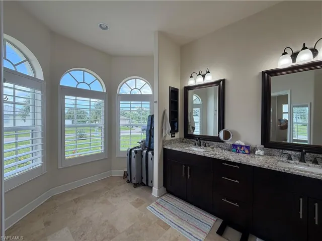 Bathroom featuring a dual vanity with dark wood cabinetry, granite-finish countertops, and rectangular framed mirrors