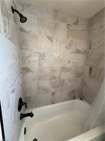 Hallway Bathtub/Shower Combo with light-toned, rectangular wall tiling