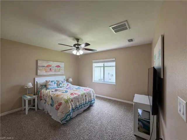 Bedroom 2 with textured carpet flooring, a window featuring horizontal blinds, and a ceiling fan with integrated lighting