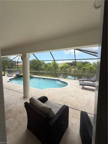 Nice covered seating area from Primary Bedroom Expansive screened lanai featuring a curved swimming pool, a water feature, and a paved deck