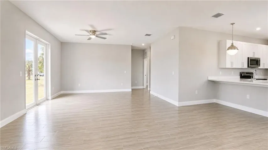 Open-concept living space featuring wood-finish flooring, a ceiling fan, and double French doors to the exterior