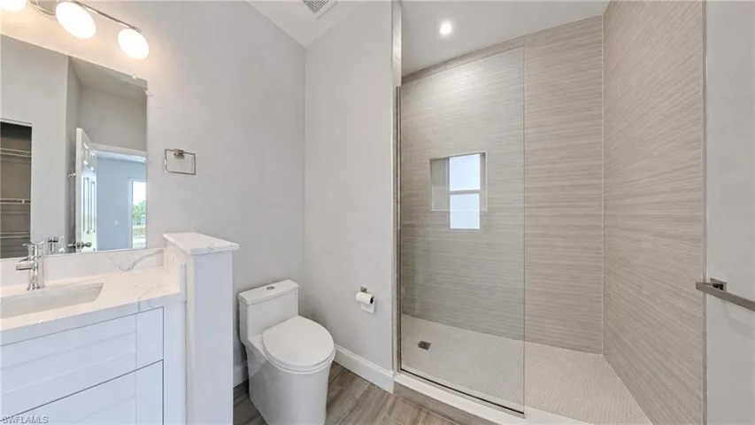 Contemporary bathroom featuring a spacious glass-enclosed shower with horizontal-patterned wall tile, a built-in shower niche, and mosaic floor tile