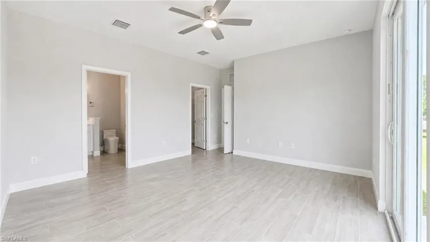 Spacious room featuring light-toned tile flooring, light gray walls, and white baseboards