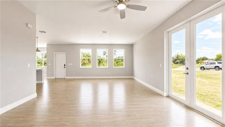 Spacious open-concept interior featuring light wood-finish tile flooring and neutral wall tones