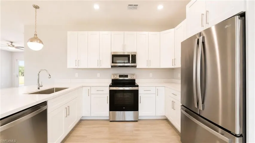 Bright kitchen featuring wood-finish flooring, white cabinetry, and stainless steel appliances