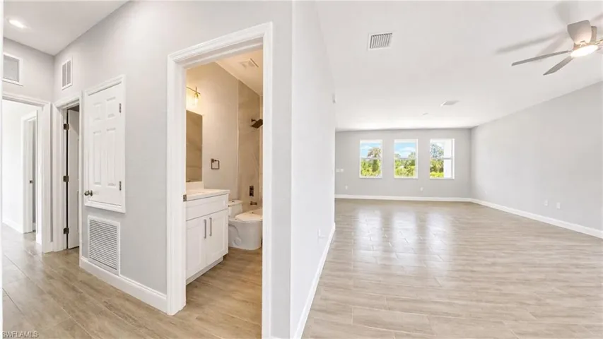 Expansive open-concept room featuring wood-finish flooring, a contemporary ceiling fan, and a three-window wall
