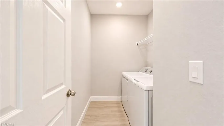 Dedicated laundry space featuring wood-finish flooring, light grey walls, and a recessed ceiling light