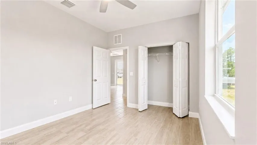 Room featuring wood-finish flooring, a ceiling fan, and a double-door closet with bifold doors