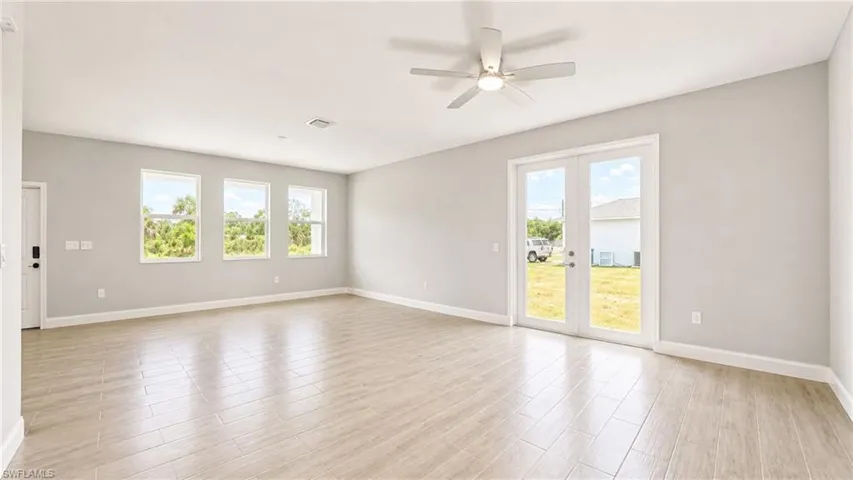 Spacious interior featuring wood-finish tile flooring, a ceiling fan, and light gray wall tones
