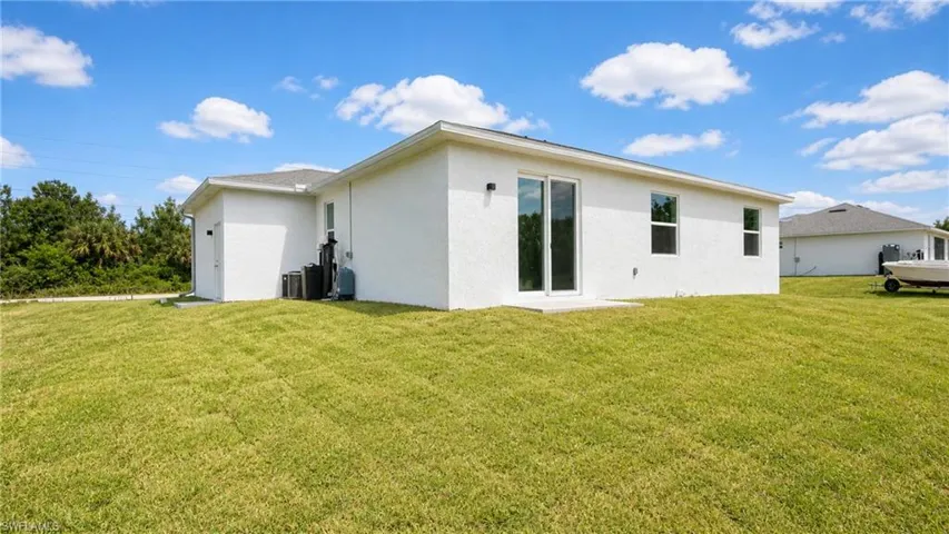 Expansive green lawn surrounds the property with a white stucco exterior