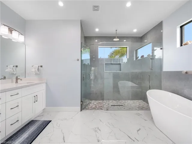 Bathroom featuring a soaking tub, vanity, a shower stall, recessed lighting, and light marble finish floors