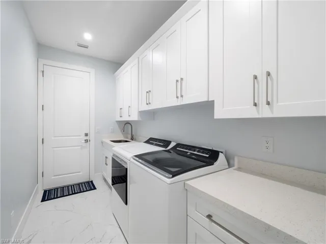 Laundry room with light marble finish floors, cabinet space, washer and dryer, and recessed lighting