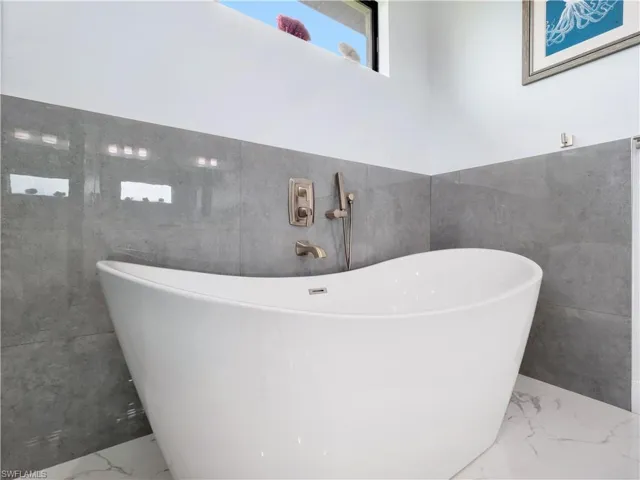 Bathroom with tile walls, a soaking tub, and marble tiled flooring