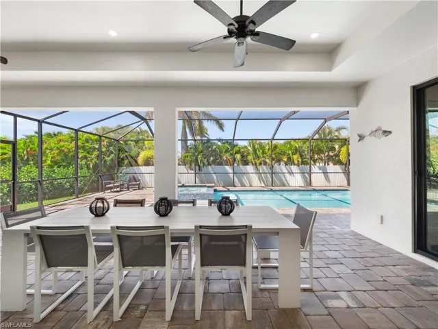 View of patio with a sunroom, outdoor dining space, glass enclosure, and a pool with connected hot tub