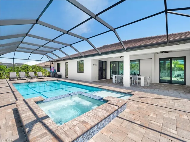 Integrated pool / hot tub featuring a sunroom, a patio area, outdoor dining area, and a lanai