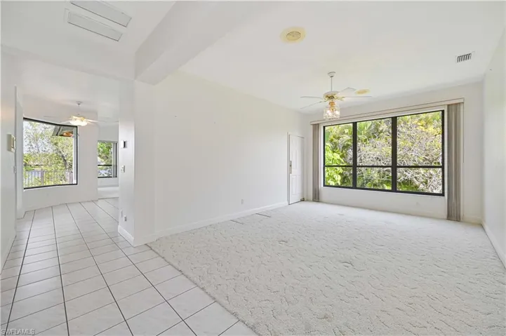 Unfurnished room with light tile patterned floors, ceiling fan, visible vents, and baseboards