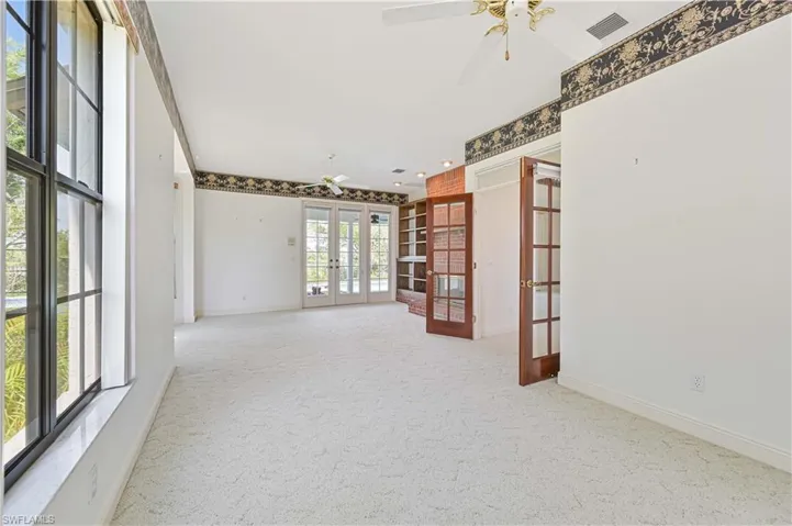 Carpeted spare room with french doors, visible vents, ceiling fan, and baseboards