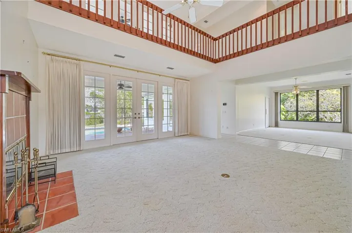 Unfurnished living room featuring visible vents, a towering ceiling, ceiling fan, carpet flooring, and french doors