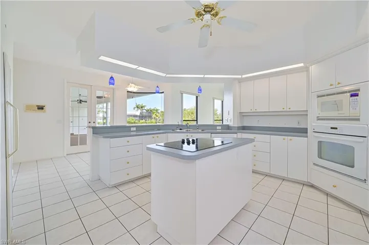 Kitchen featuring a peninsula, white appliances, light tile patterned flooring, and a sink