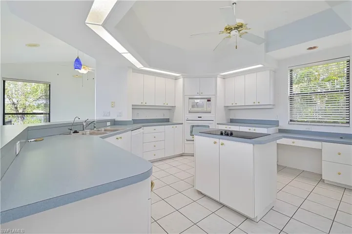 Kitchen with white appliances, a healthy amount of sunlight, ceiling fan, and a sink