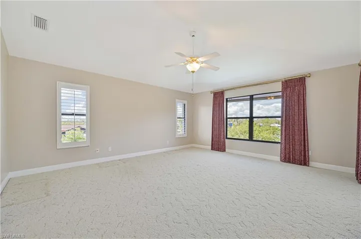 Unfurnished room with baseboards, visible vents, light colored carpet, ceiling fan, and vaulted ceiling
