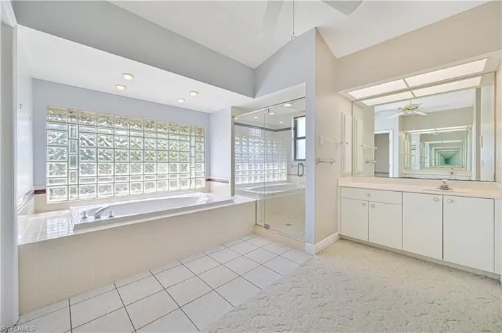 Full bath featuring a garden tub, tile patterned flooring, vanity, a ceiling fan, and a stall shower