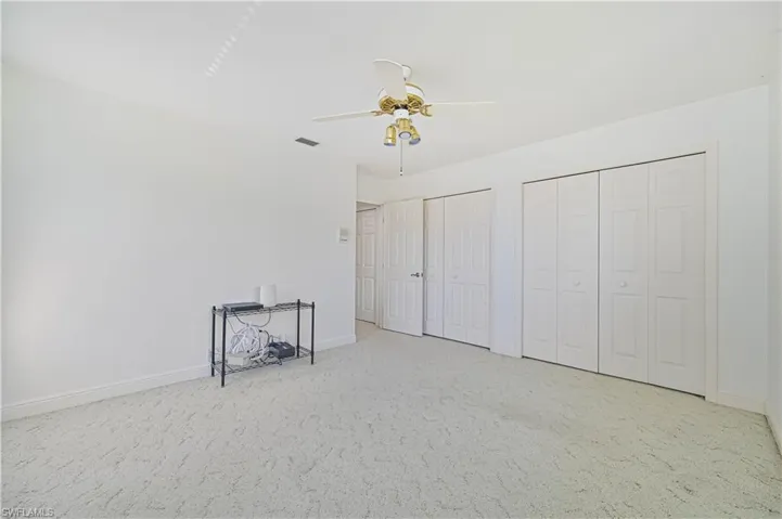 Unfurnished bedroom with carpet floors, visible vents, baseboards, and two closets