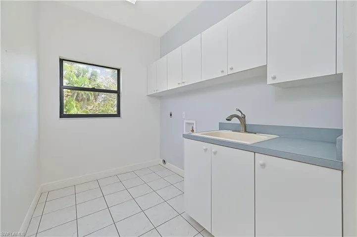 Laundry room featuring cabinet space, baseboards, hookup for a washing machine, hookup for an electric dryer, and a sink