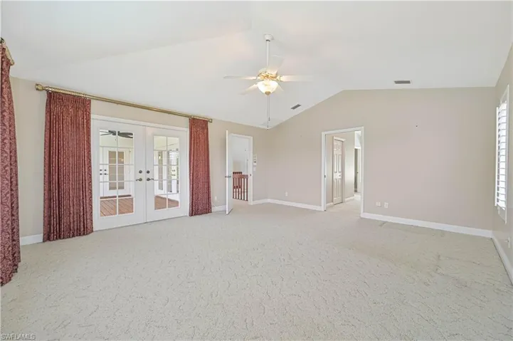 Spare room with lofted ceiling, ceiling fan, light colored carpet, visible vents, and french doors