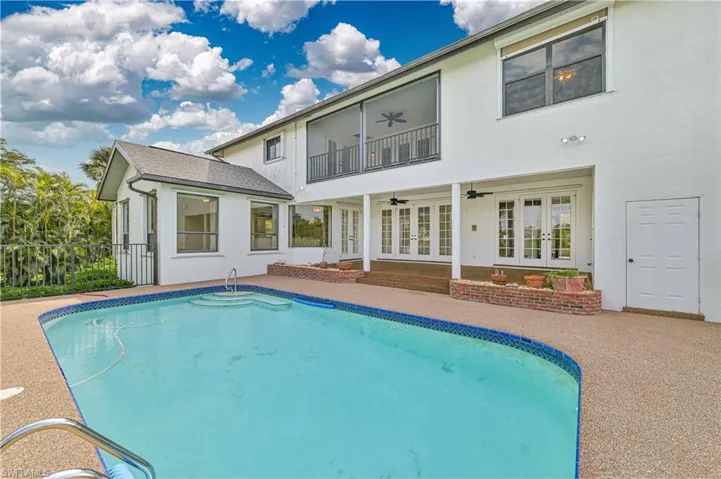 Back of house with french doors, stucco siding, a ceiling fan, a balcony, and an outdoor pool