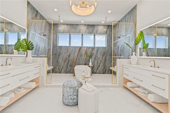 Full bath featuring light marble finish flooring, a marble finish shower, two vanities, recessed lighting, and stone wall