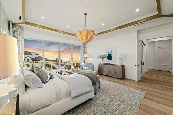 Bedroom featuring light wood-style flooring, recessed lighting, a chandelier, a barn door, and ornamental molding