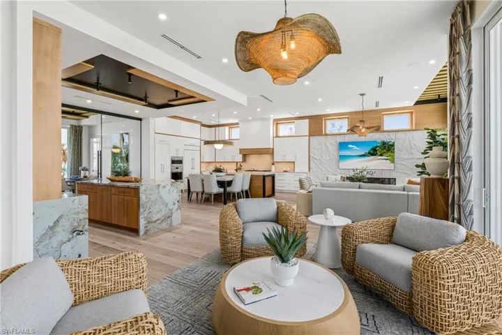 Living area with a tray ceiling, recessed lighting, and light wood-style floors