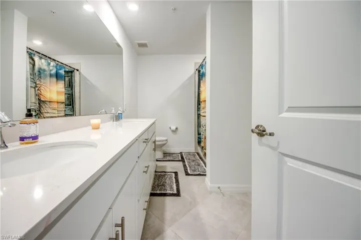 Full bath with a shower with curtain, double vanity, and recessed lighting