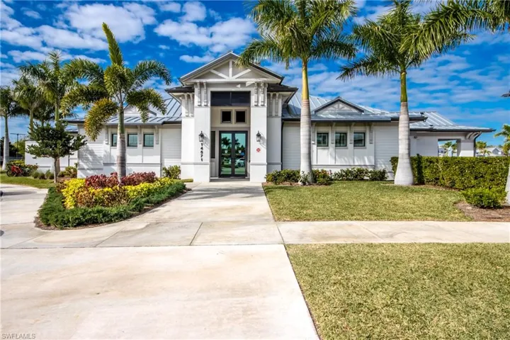 View of front facade with french doors, a front lawn, stucco siding, driveway, and a standing seam roof
