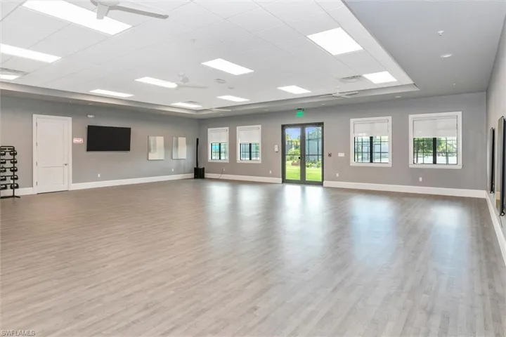 Unfurnished room featuring a ceiling fan, light wood-type flooring, a drop ceiling, and french doors