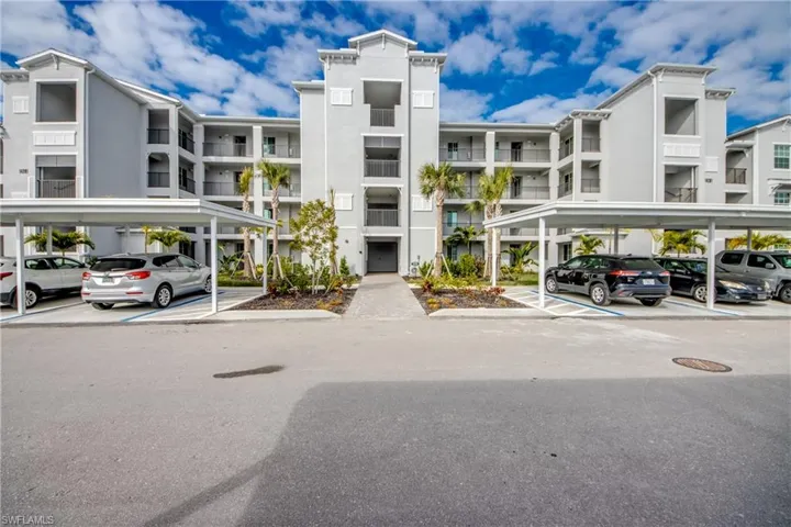 View of apartment building / complex featuring covered parking